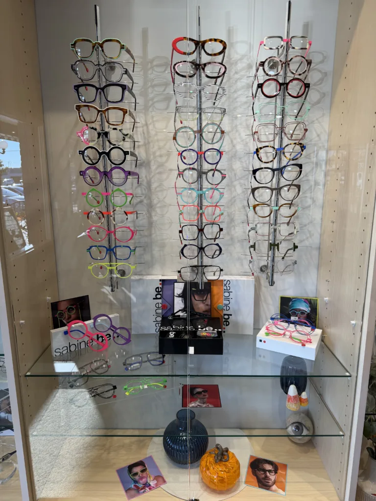 A glass display case filled with colorful eyeglass frames in a variety of shapes and styles, all available at Eyewearhaus.