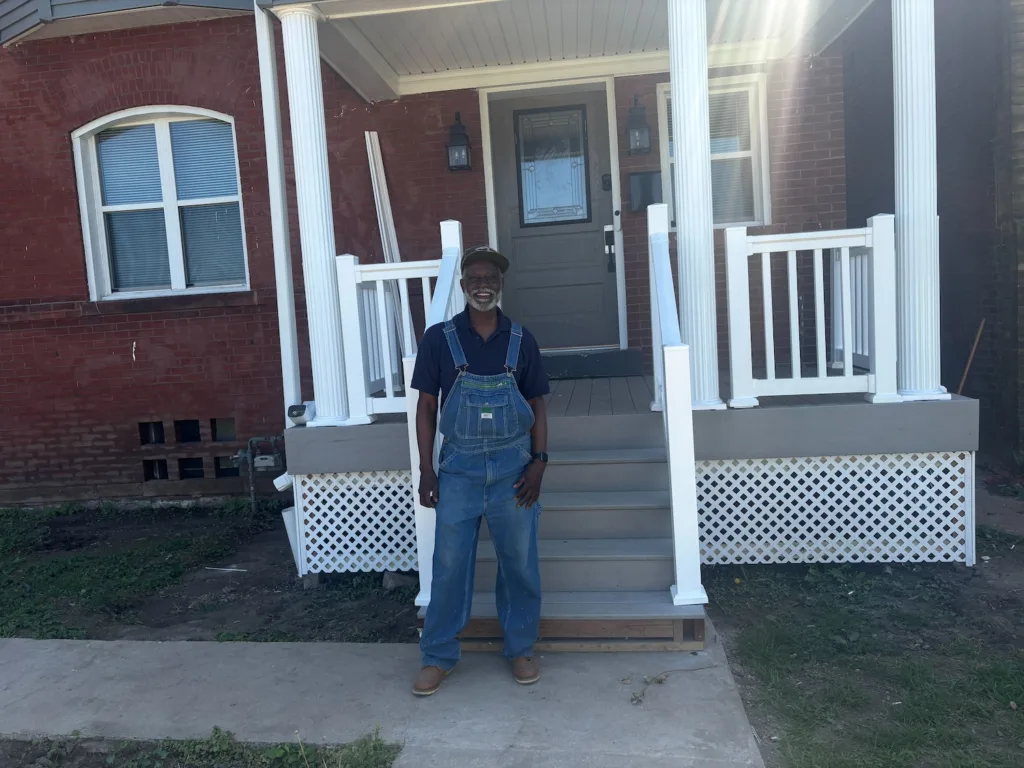 A man beams before his freshly painted porch.