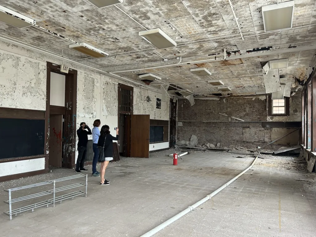 People stand inside a dilapidated school building.