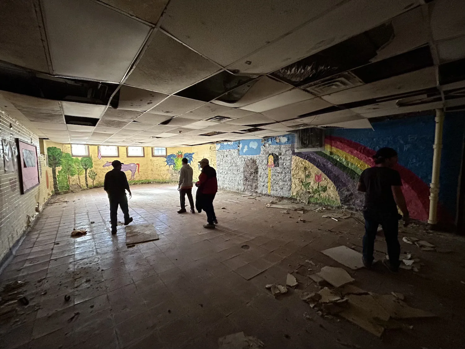 A group of men stand inside a dilapidated former school.