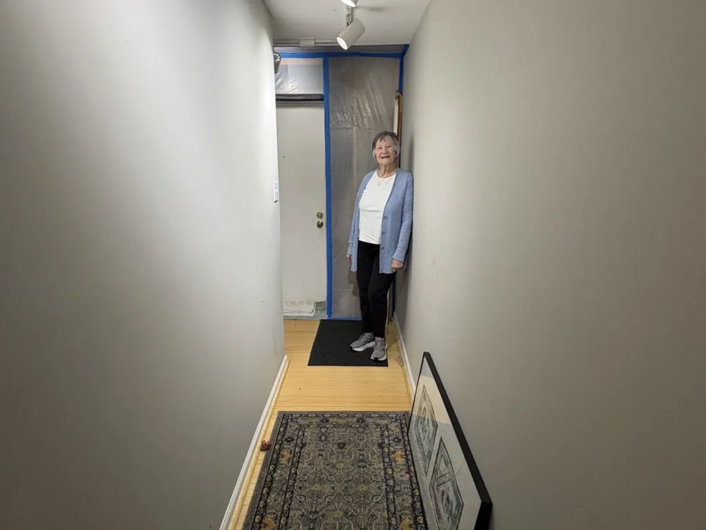 A woman stands next to a tarped off unit.