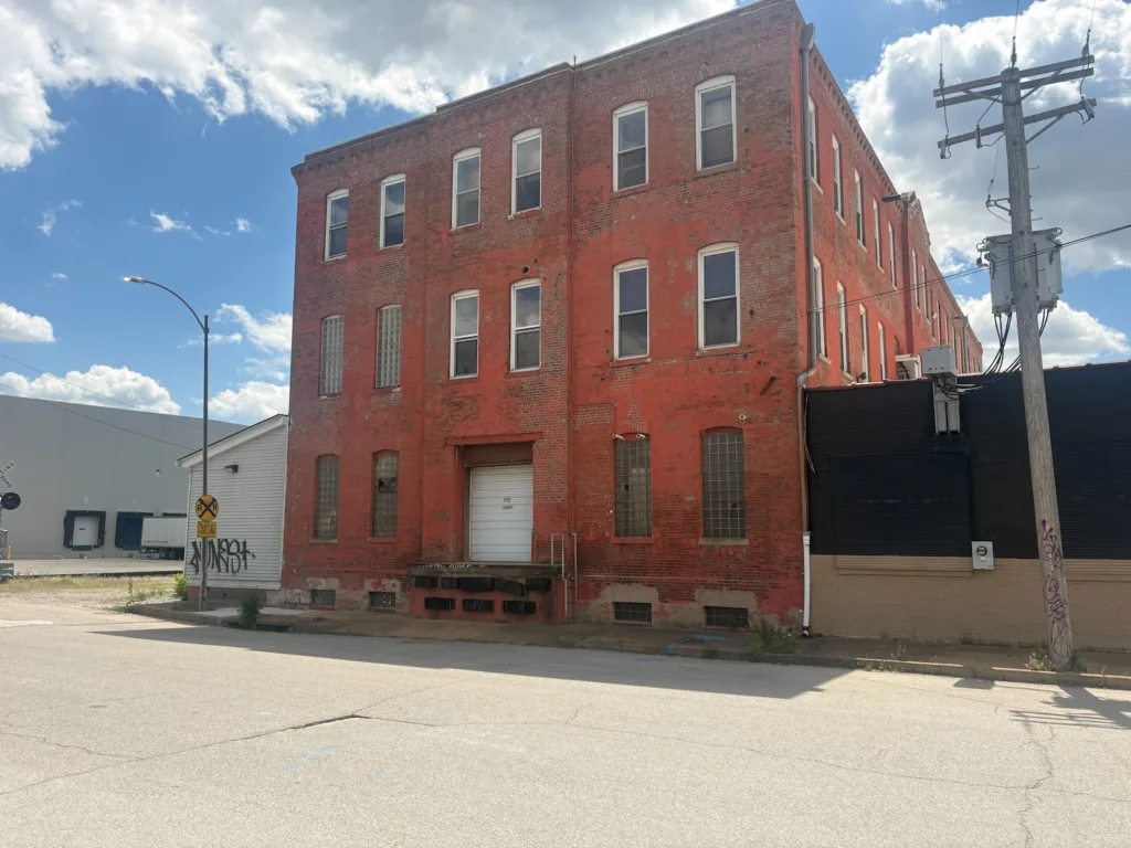 A red brick building with an adjacent black-painted building to its side.