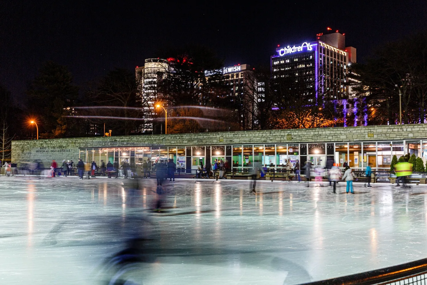 A row of hospitals glimpsed looming over an ice skating rink.